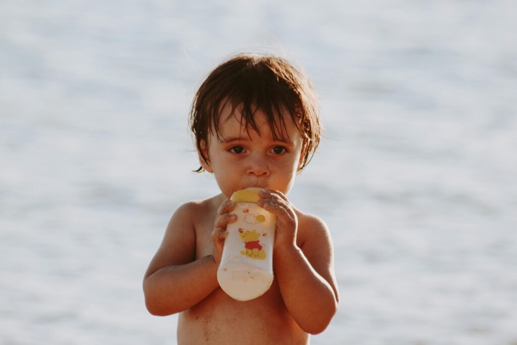Niño con un biberón en la playa